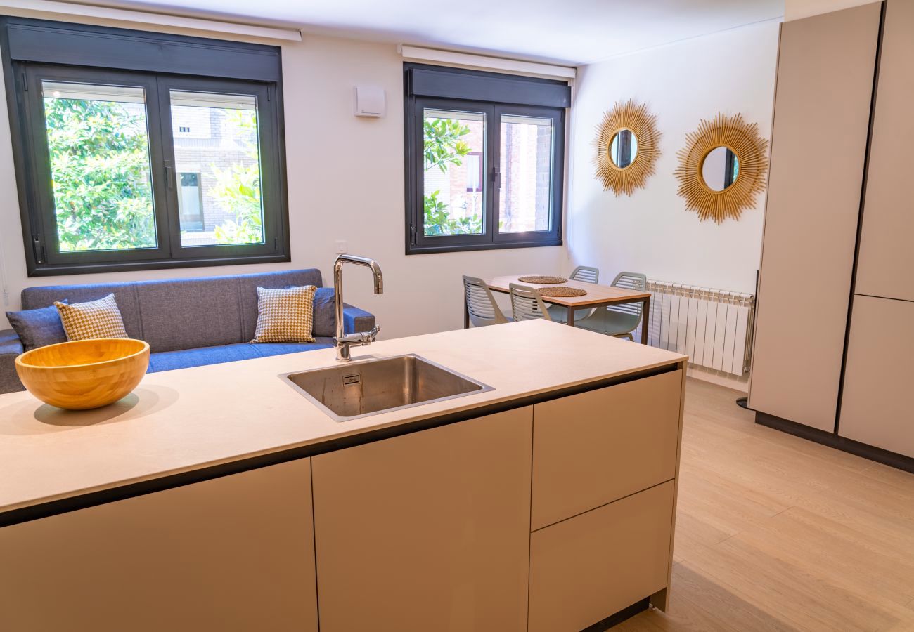 Encimera de cocina con fregadero, cuenco de madera y comedor al fondo