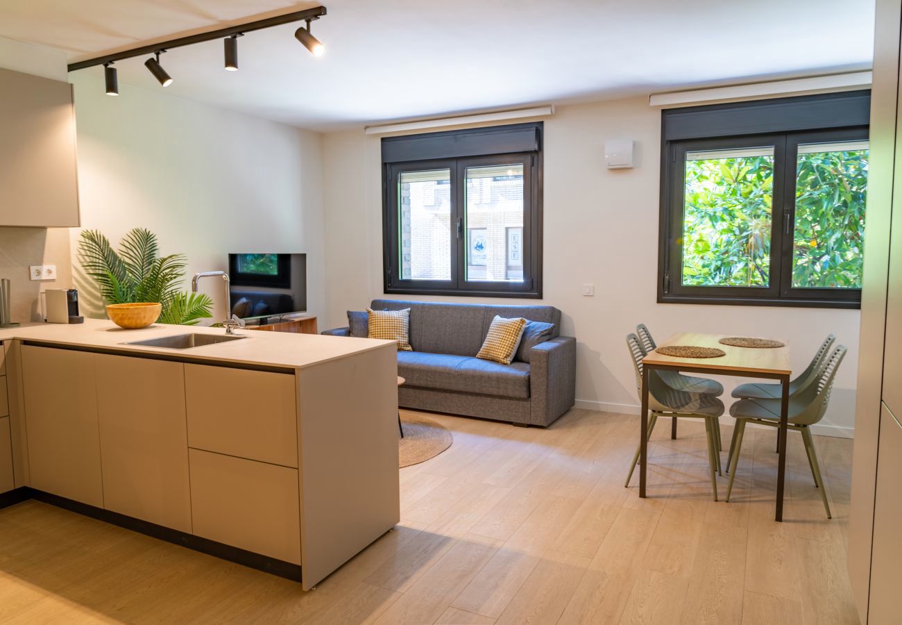 Salón con televisor y columna de armarios de cocina con microondas