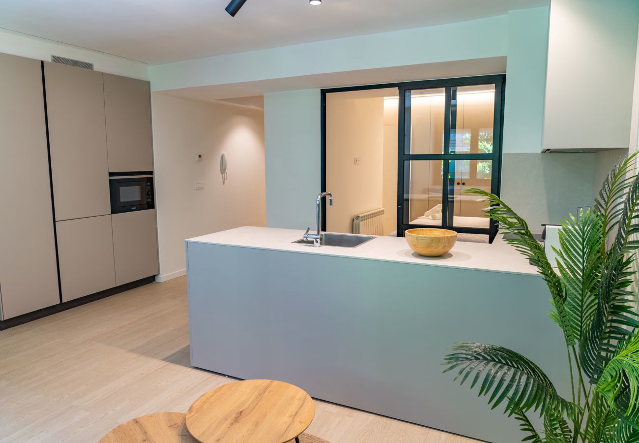 Isla de cocina con grifo cromado y vista al dormitorio a través del cristal