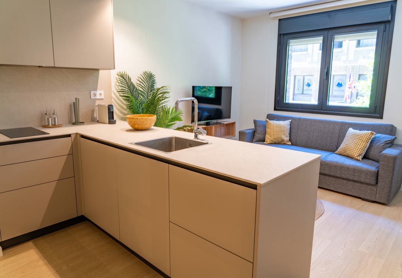 Cocina en L con vista a la calle y salón con sofá al fondo