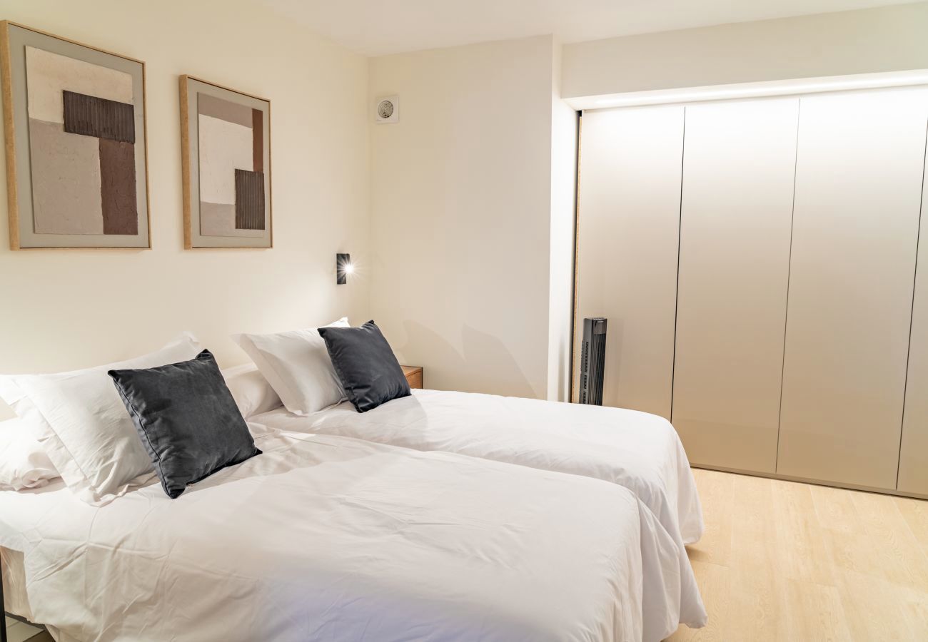 Dormitorio con cojines oscuros y armario empotrado con luz integrada, Urban 2 habitaciones