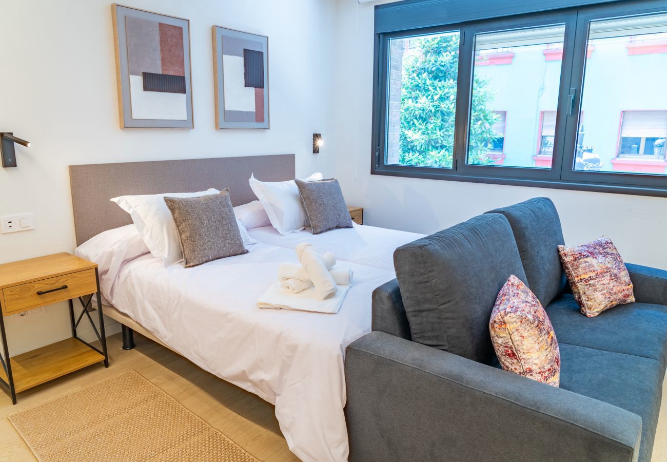 Estudio con cama, sofá y ventana amplia con vistas al patio, apartamento Urban Estudio