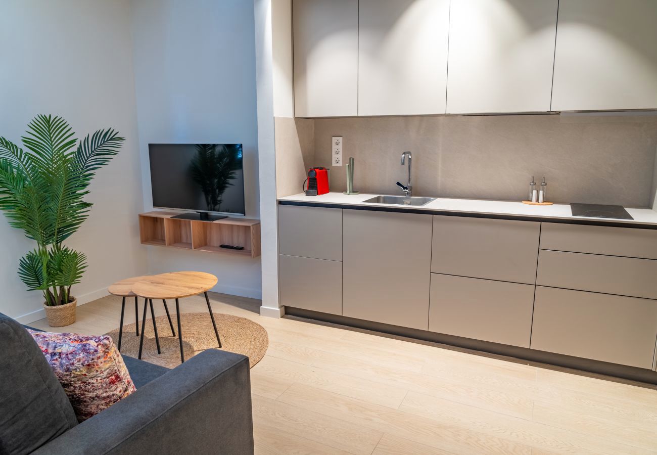 Zona de estar con televisor y cocina abierta, apartamento Urban Estudio