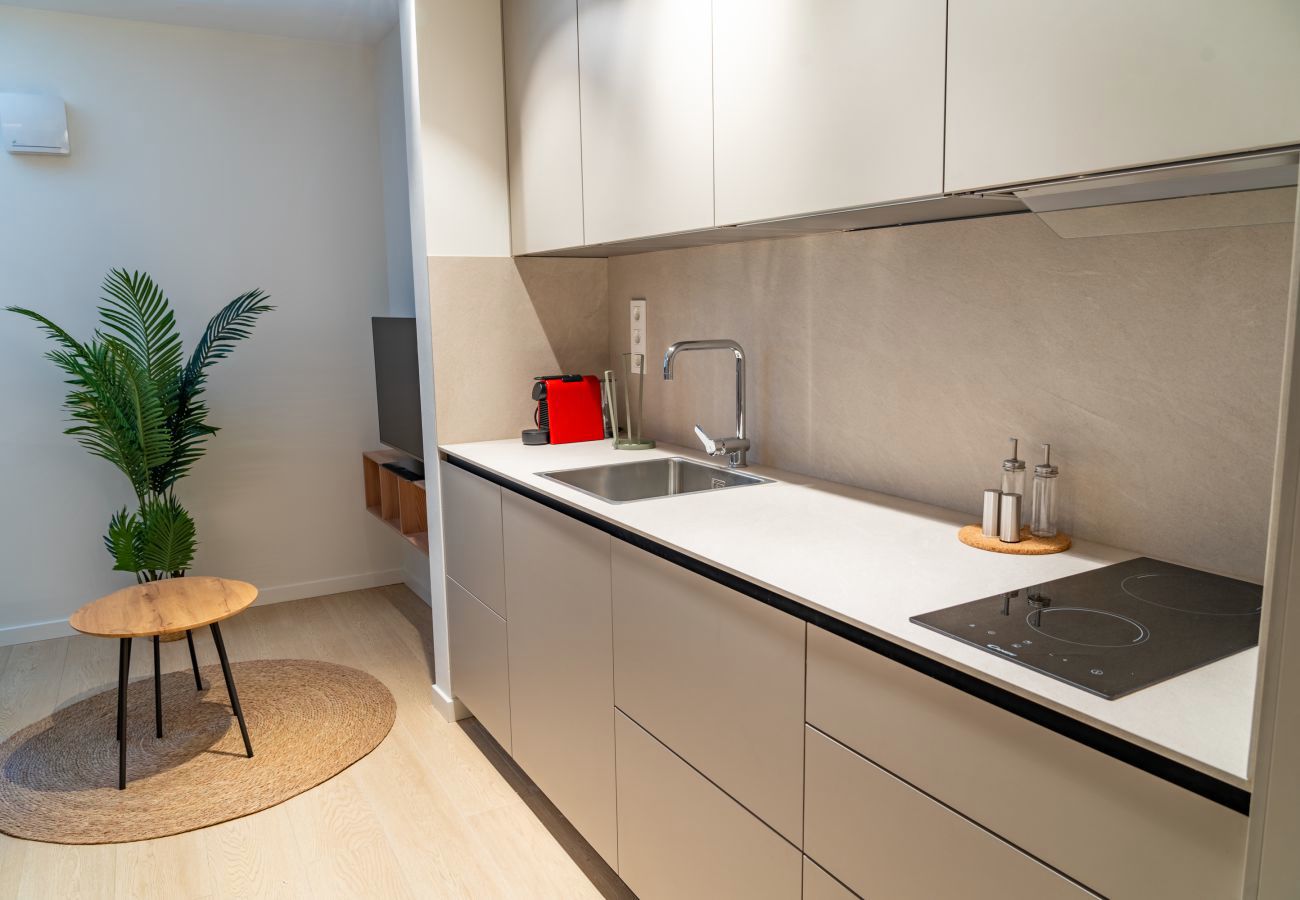 Cocina en línea con muebles claros y encimera despejada, apartamento Urban Estudio