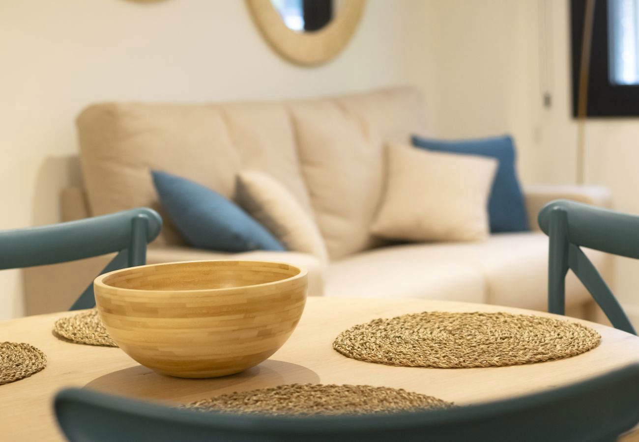 Detalle de mesa de comedor con cuenco de madera y sillas azules, apartamento Superior