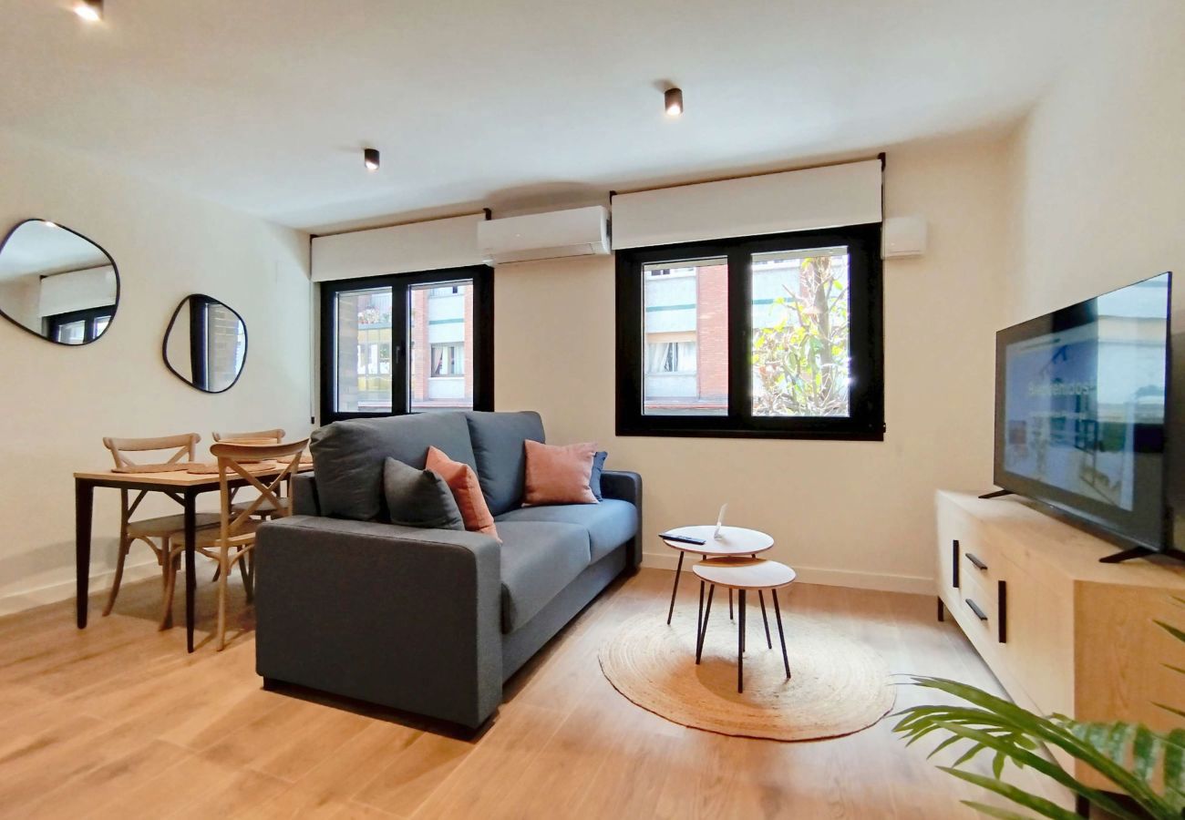 Salón con cocina abierta y sofá con cojín mostaza, apartamento Superior