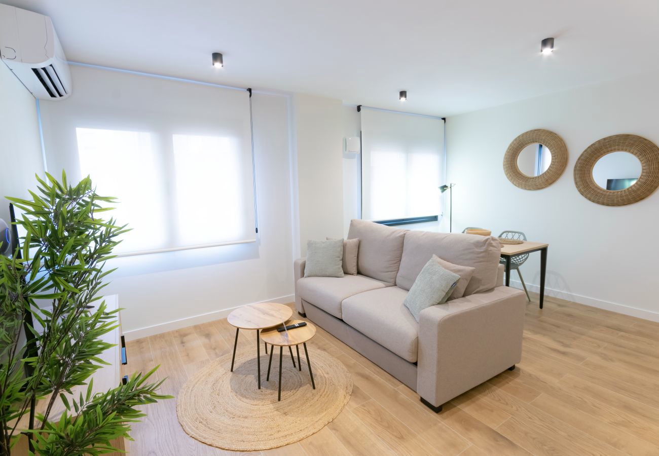 Salón con sofá beige y espejos redondos de fibra natural, apartamento Urban Plus