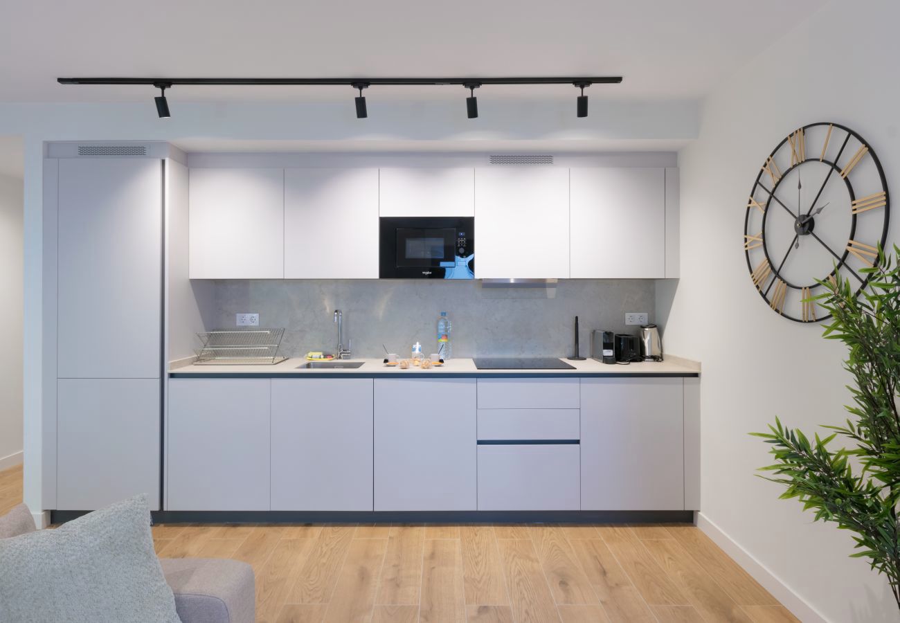 Cocina con muebles blancos y microondas integrado, apartamento Urban Plus