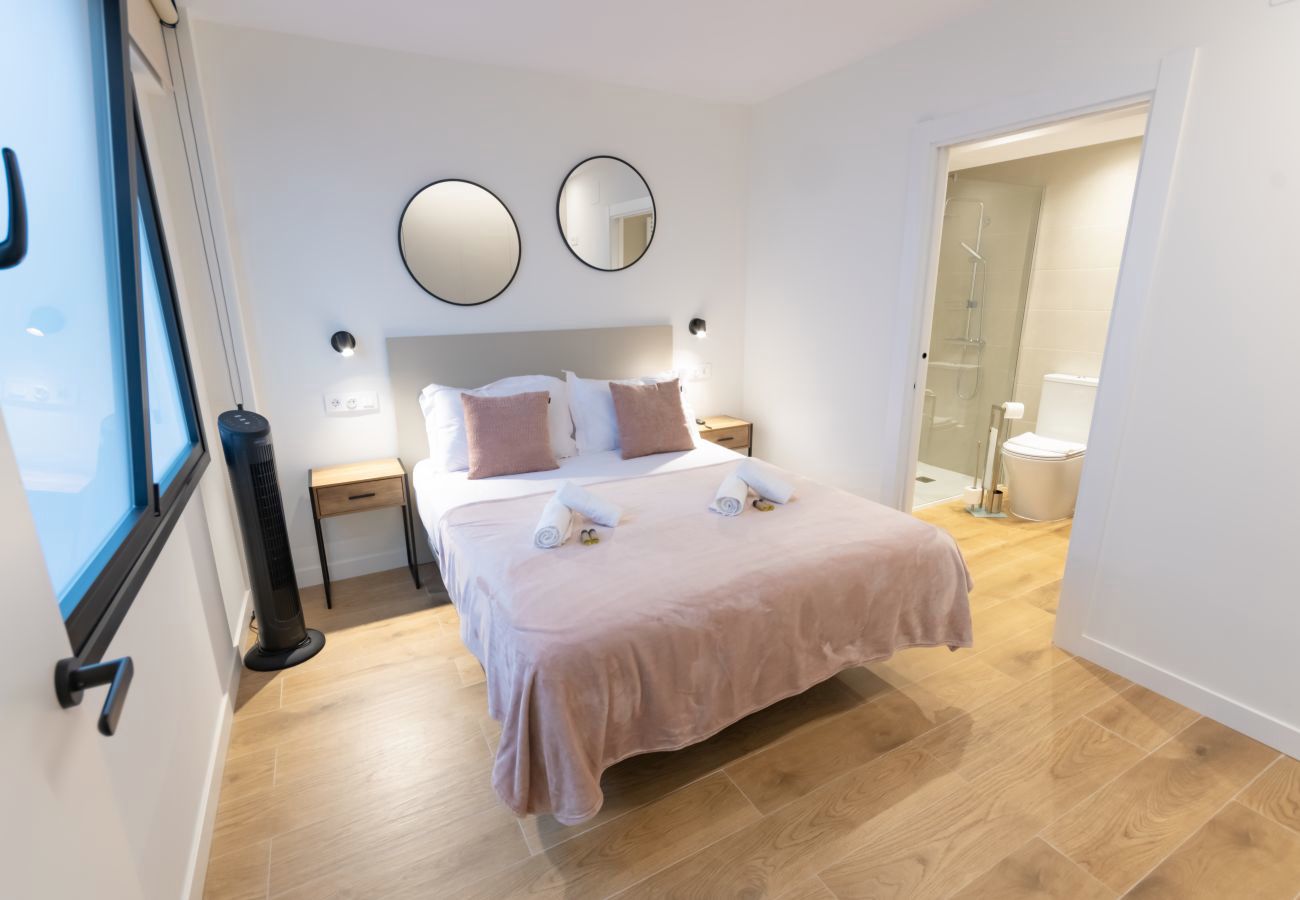 Dormitorio con espejos redondos y manta rosa junto al baño, Urban Plus