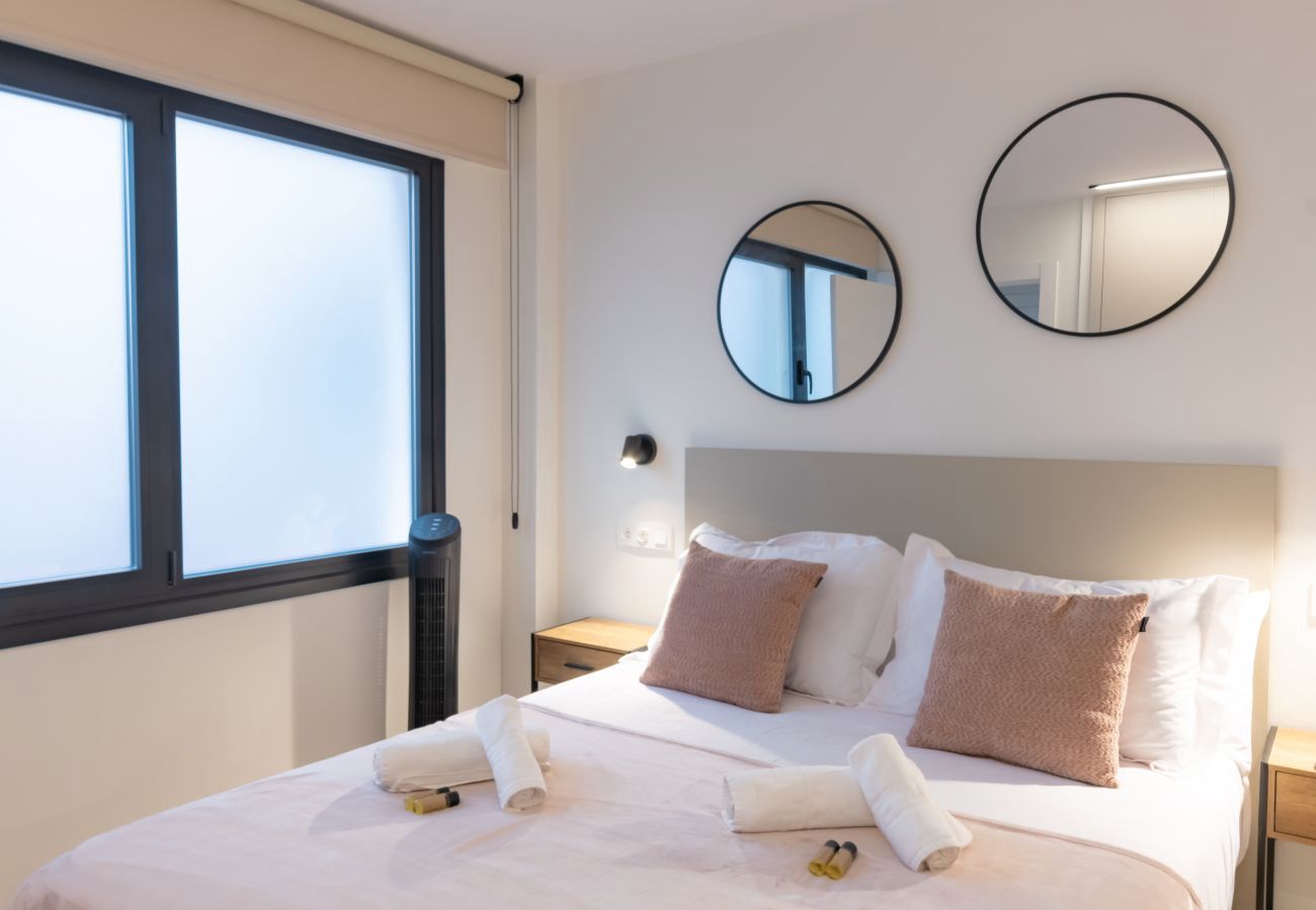 Dormitorio con espejos redondos y toallas enrolladas junto a la ventana, Urban Plus
