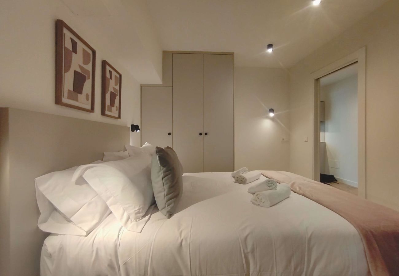 Dormitorio con cabecero topo y cojines grises junto al armario, Urban Premium