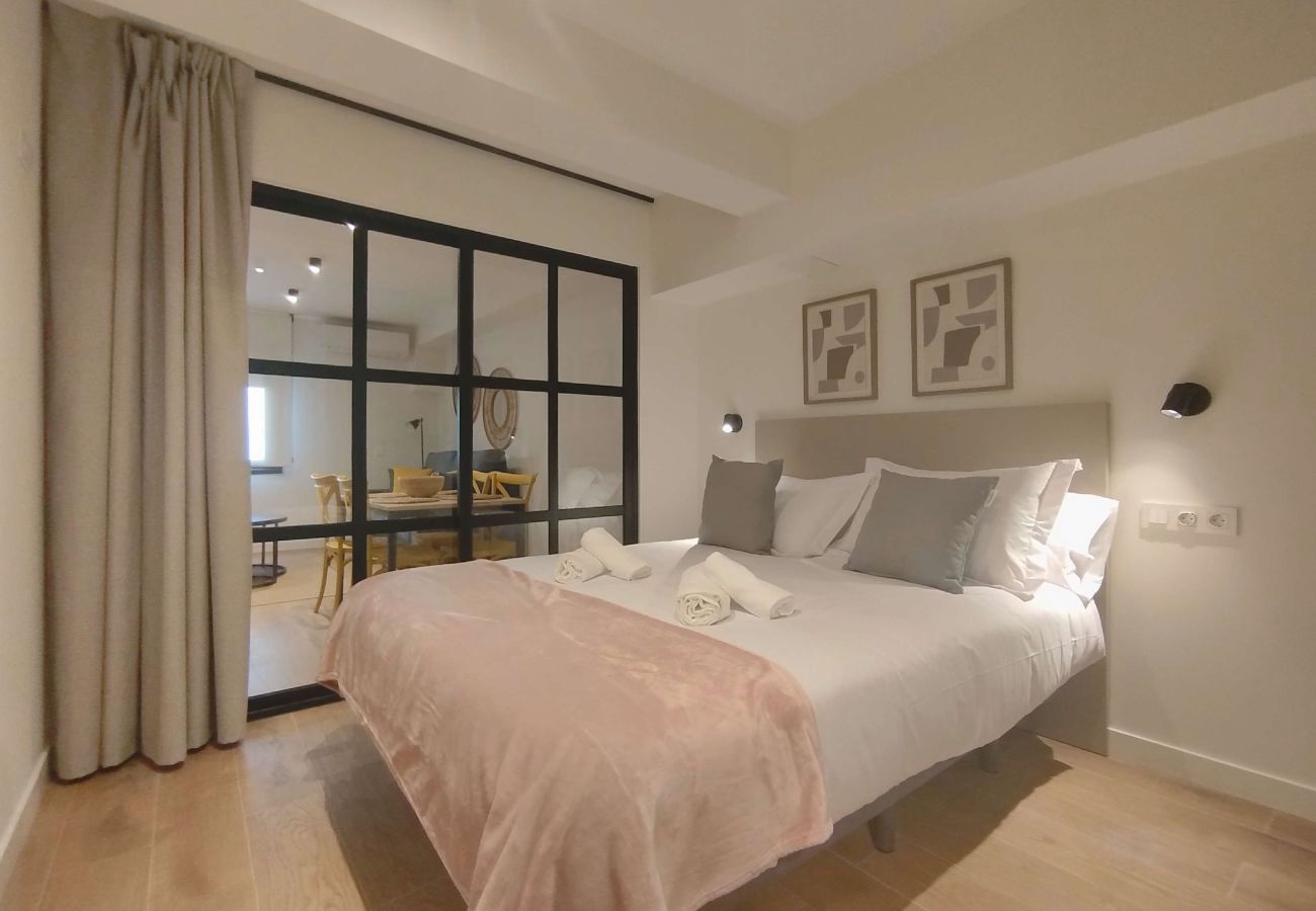 Dormitorio con cuadros abstractos y manta rosa palo, apartamento Urban Premium