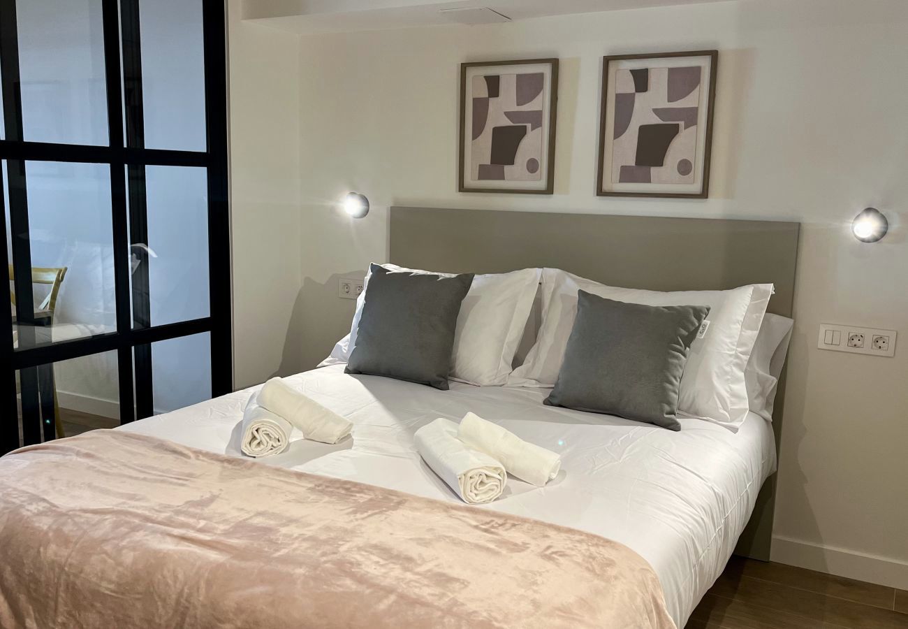 Dormitorio con cuadros abstractos y toallas enrolladas, apartamento Urban Premium