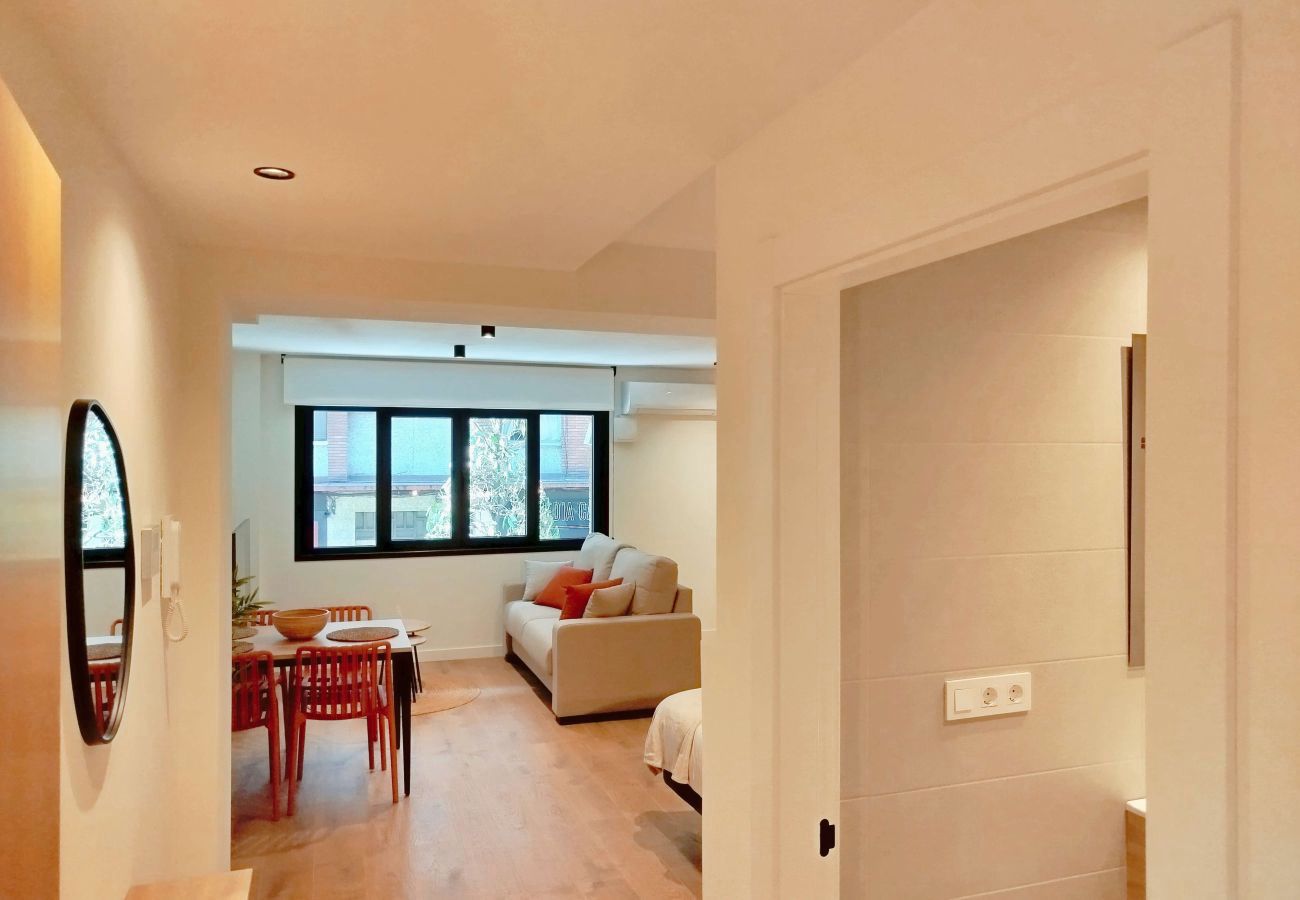 Pasillo de entrada con espejo redondo y vista al salón, apartamento Urban Suite