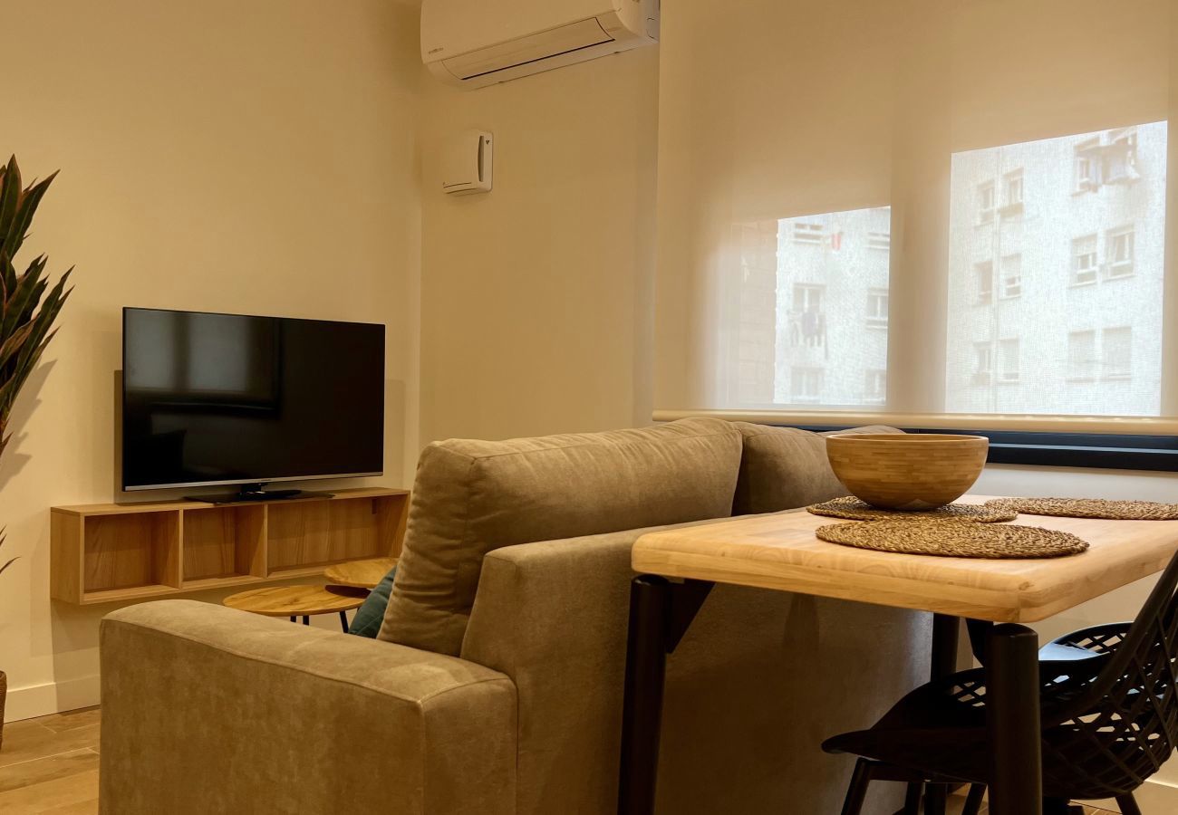 Salón con sillón, televisor y aire acondicionado junto a la ventana, Urban Suite
