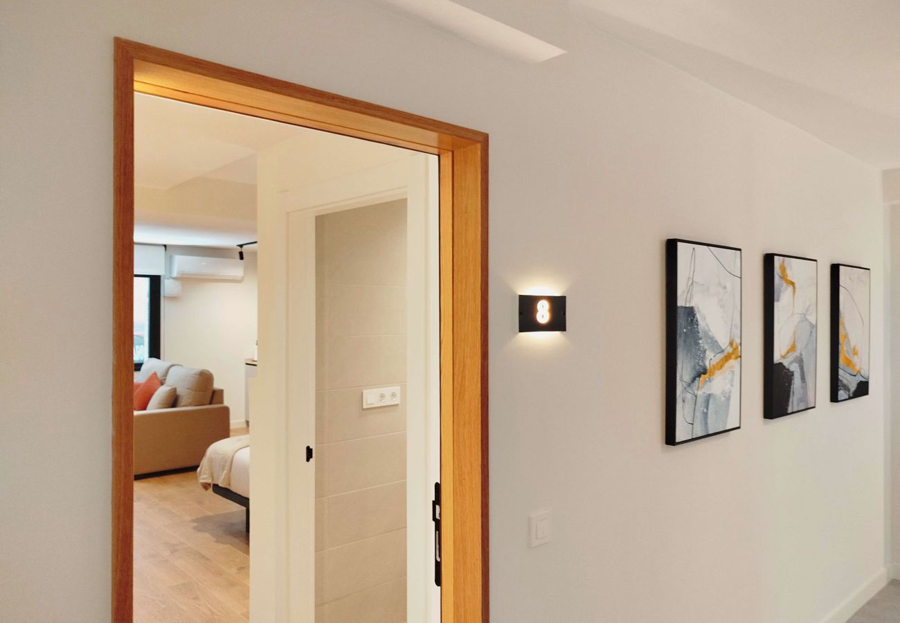 Pasillo de entrada de madera con cuadros abstractos junto al dormitorio, Urban Suite