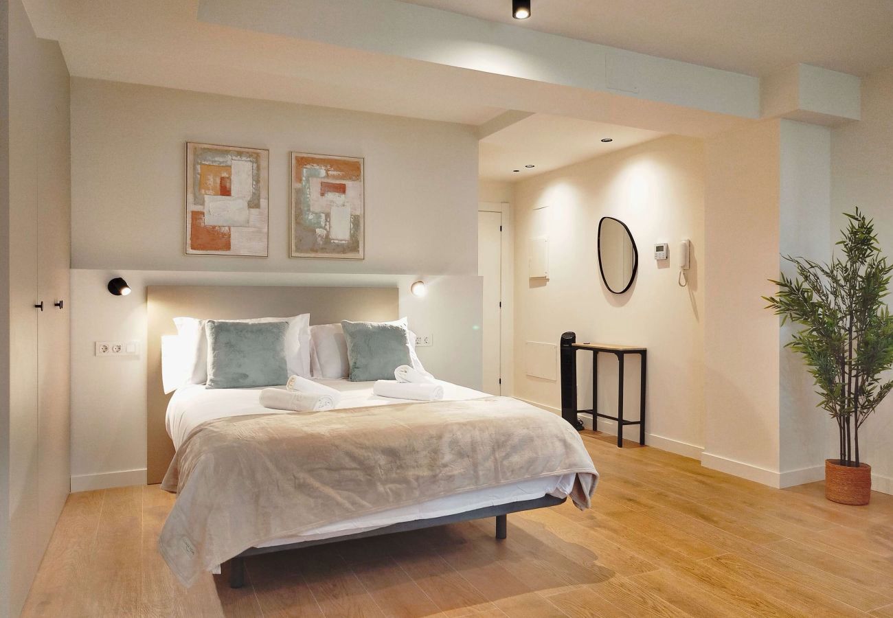 Dormitorio con cojines verde salvia y toallas enrolladas junto al pasillo, Urban Suite
