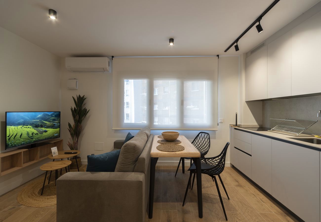 Salón con cocina abierta y televisor junto a la mesa de comedor, Urban Suite