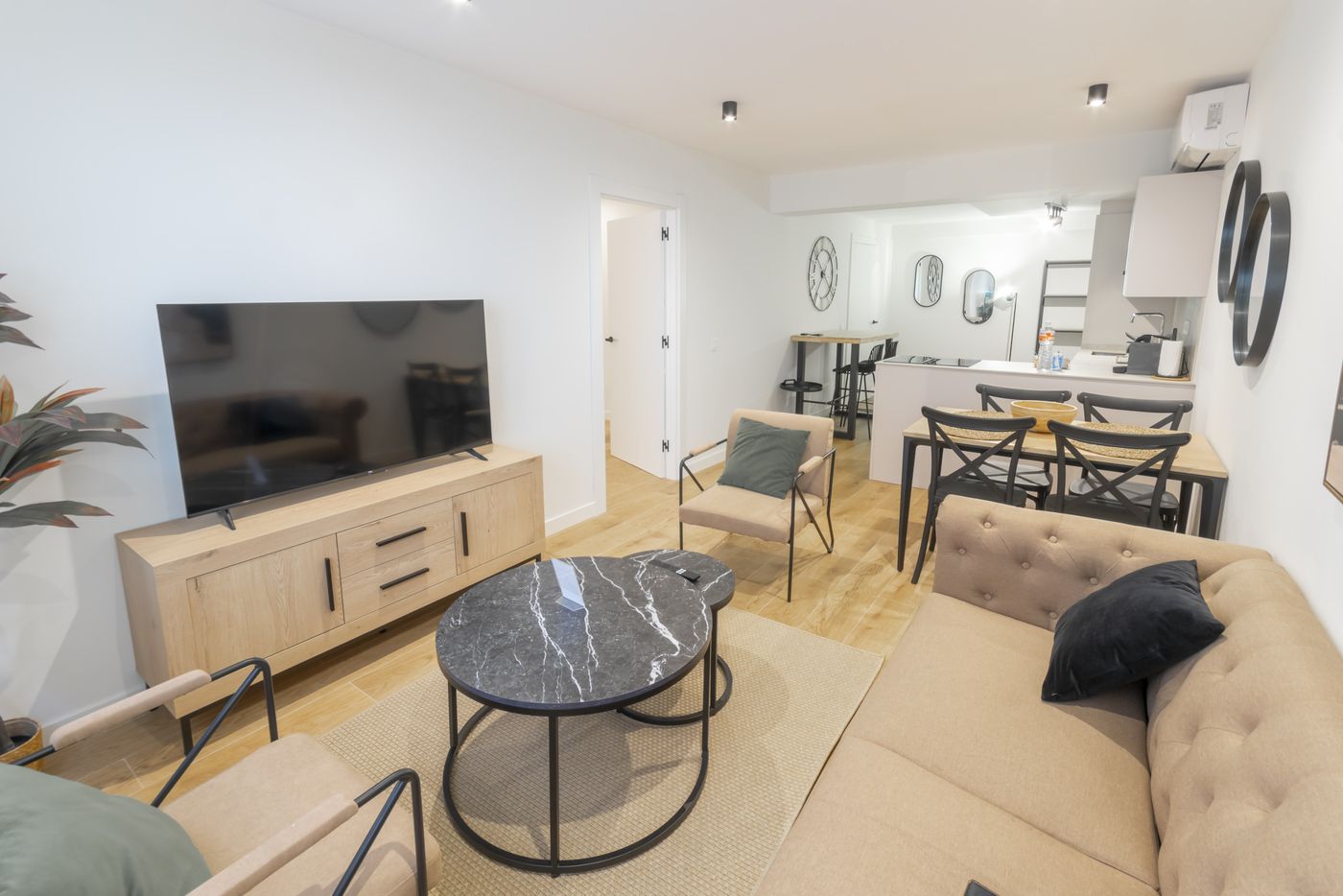 Open-plan lounge and kitchen with TV, coffee table and armchairs, Urban Superior apartment
