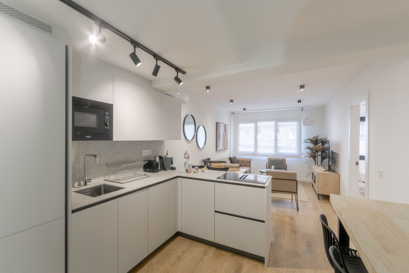 Cocina en línea abierta al salón con muebles blancos, apartamento Urban Superior
