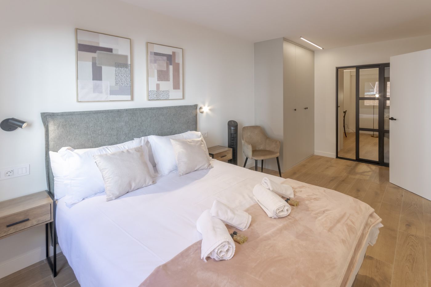 Cama de matrimonio con toallas enrolladas junto al armario, apartamento Urban Superior