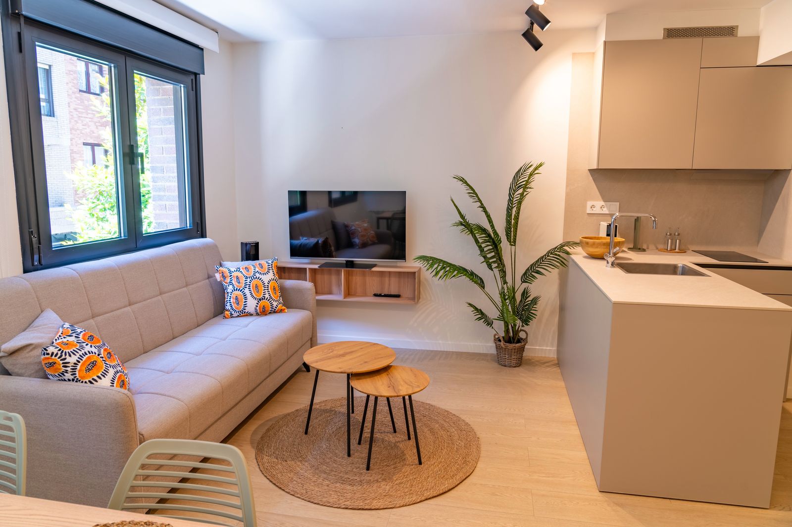 Salón luminoso con sofá gris, mesa de comedor y cocina en isla
