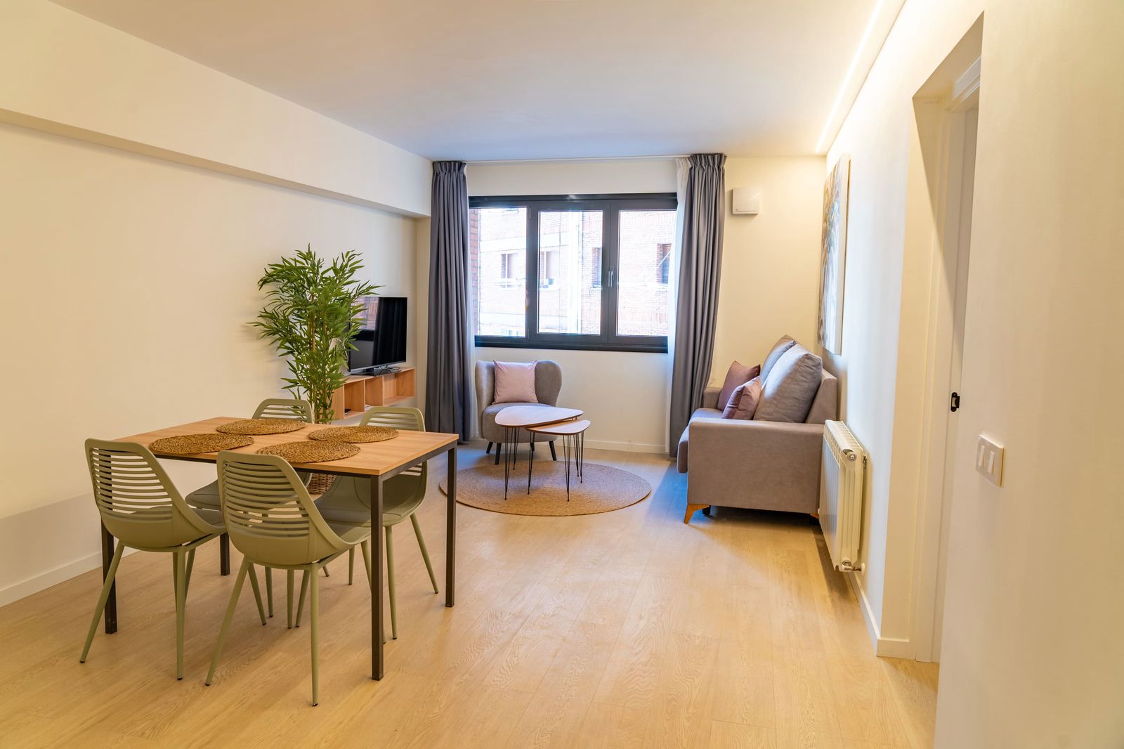 Lounge with round dining table, sofa and curtains by the window